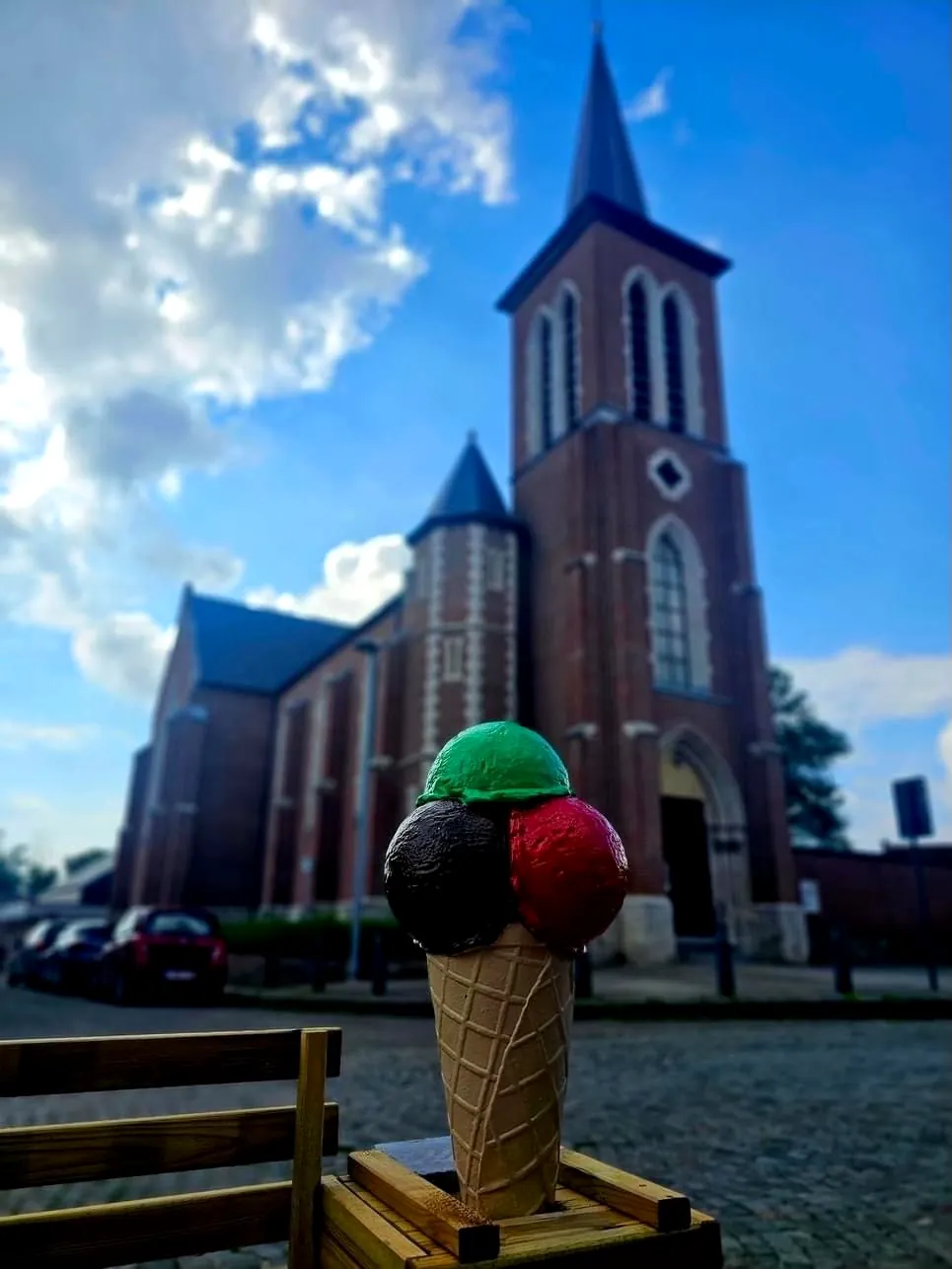 Een grote ijshoorn met drie bollen voor de kerk van Bost